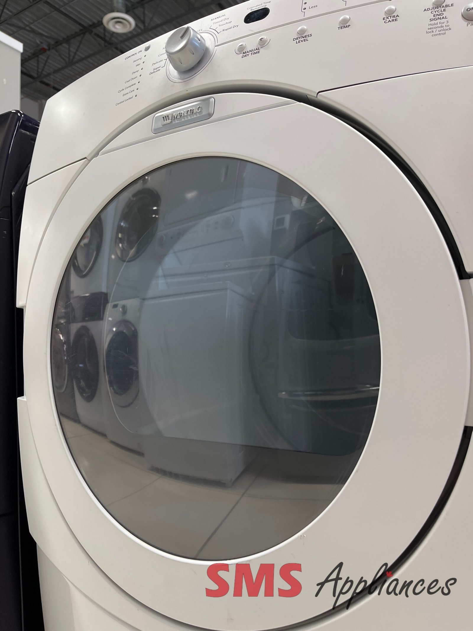 Refurbished-Dryers-YMED9600SQ-6-scaled-1.jpg Close-up of a white front-loading Maytag washing machine with a circular glass door and control panel at the top edge